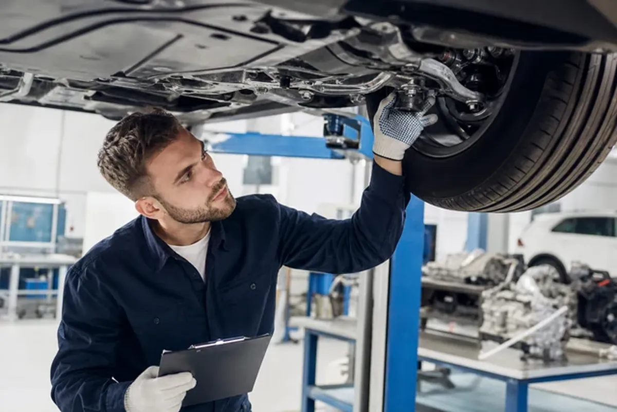 Techniker prüft Fahrwerk an der Hebebühne in heller Werkstatt